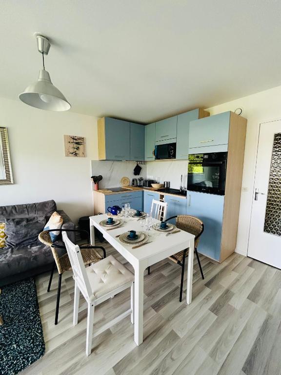 a kitchen and living room with a white table and chairs at La case du trimaran in Cabourg