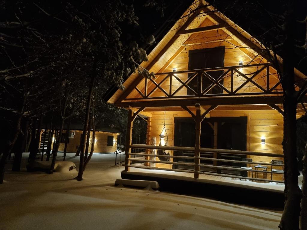 a log cabin in the snow at night at Domki Wzgórze Kamień in Józefów