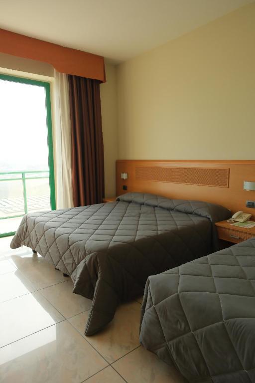 two beds in a hotel room with a window at Hotel Panorama in Cambiano