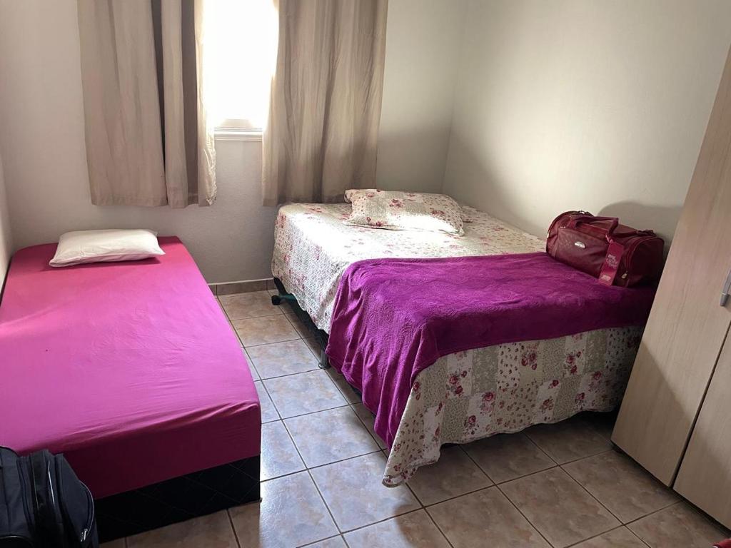 two beds in a small room with purple sheets at Casa de piscina em Delfinopolis área central 2 suítes in Delfinópolis