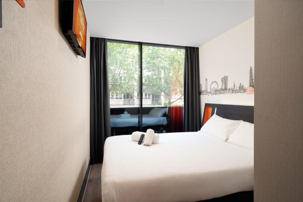 a hotel room with a white bed and a window at easyHotel London City Shoreditch in London