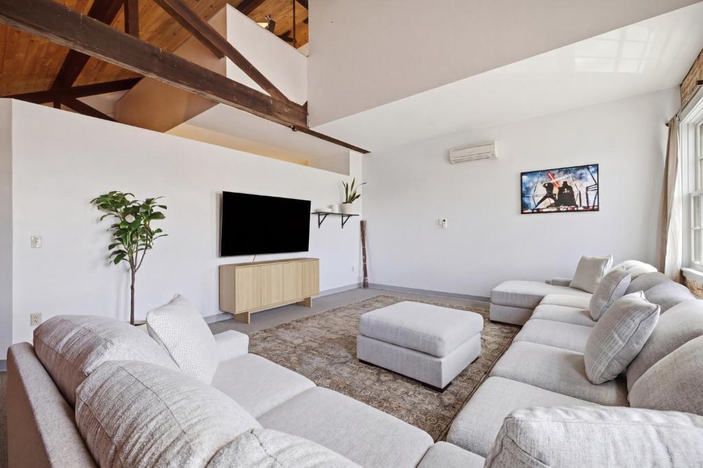 a living room with white furniture and a flat screen tv at Gorgeous downtown apartment with loft in Hartford