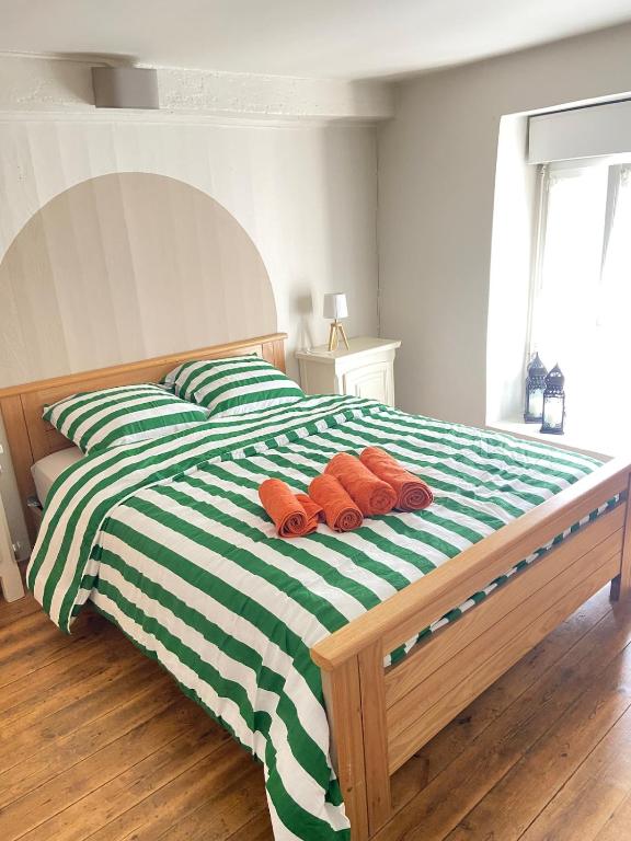 a green and white bed with three pillows on it at Maison Basse in Malestroit