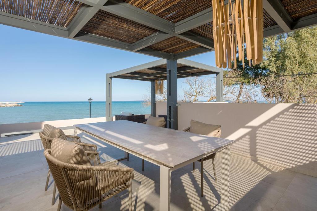 a table and chairs on a patio with the ocean at Antimo Villas - Gallini Beach House in Zakynthos
