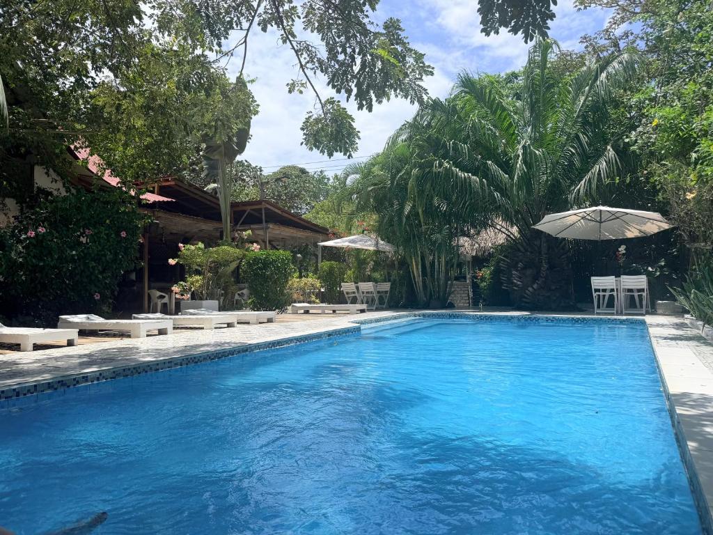 a swimming pool with an umbrella and tables and chairs at Kawabonga in Palomino
