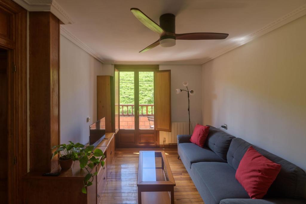 a living room with a blue couch and a ceiling fan at Casa Salamó in Ampuero