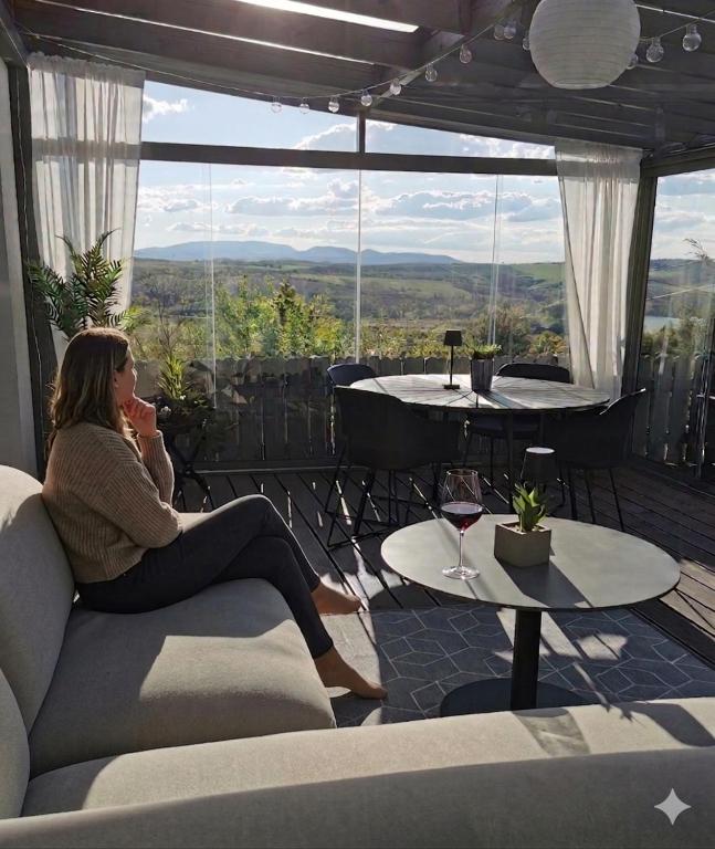 a woman sitting on a couch on a balcony with a view at Messzikék in Egerszalók