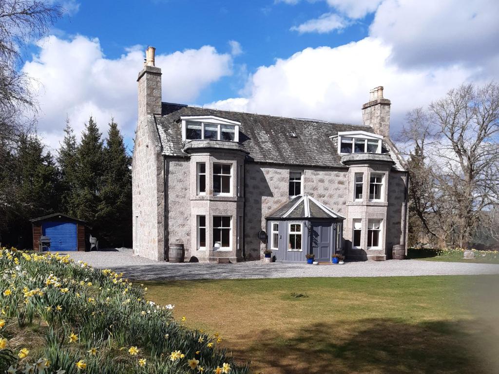 a large stone house with a lawn in front of it at Achnagonlin House in Grantown on Spey