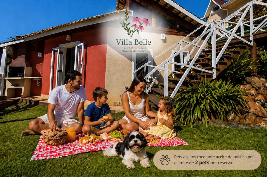 a family sitting on a picnic blanket with a dog at Villa Belle Chalés in Campos do Jordão