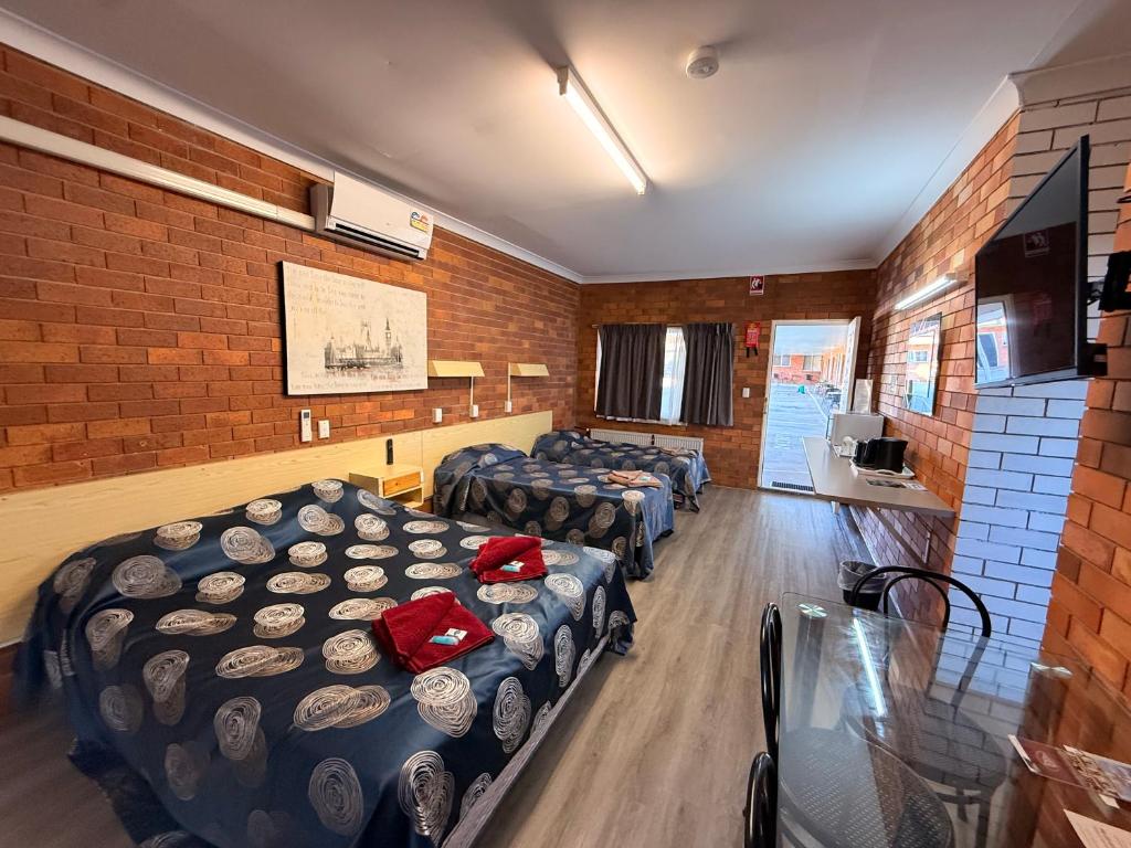 a room with four beds with hats on them at Glen Innes Lodge Motel in Glen Innes