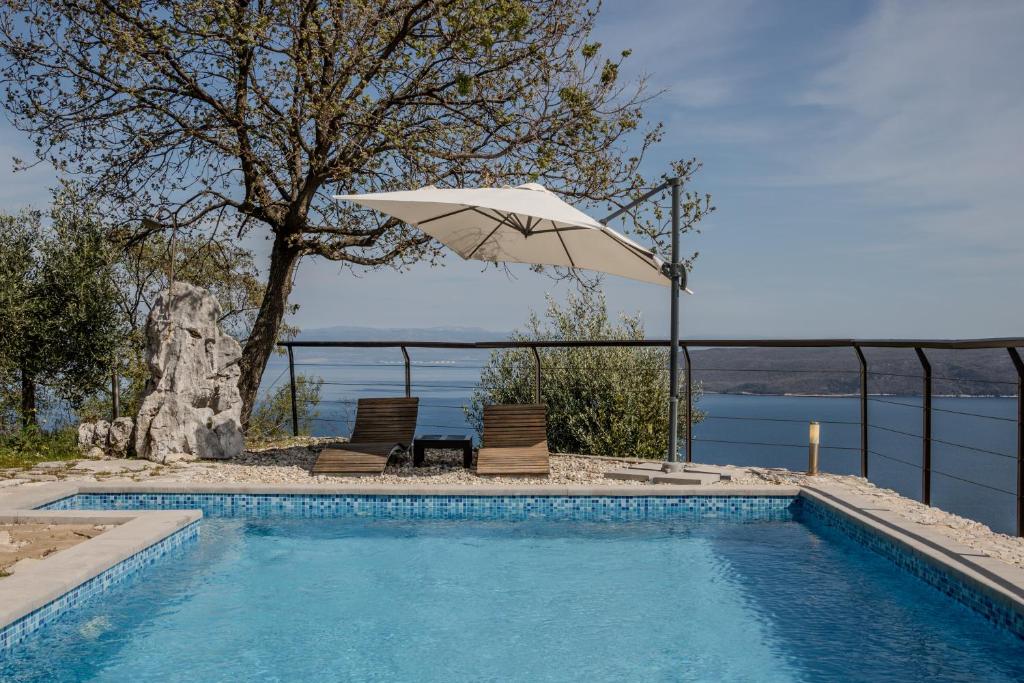a swimming pool with an umbrella and two chairs at Refugio Ivanini in Zagorje
