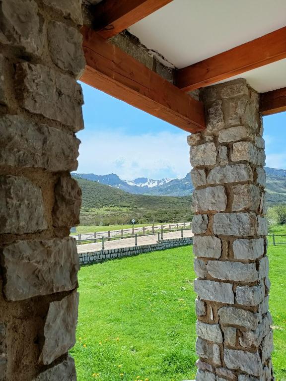 a window in a stone wall looking out at a field and mountains at La casa del Torreón in San Isidro