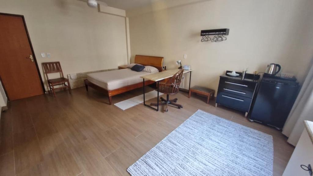 a bedroom with a bed and a desk and a table at Suíte Individual, ampla, aconchegante e com 2 ventiladores! in Vitória