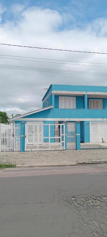 a blue building with a white fence in front of it at Aluguel casa azul in Capão da Canoa