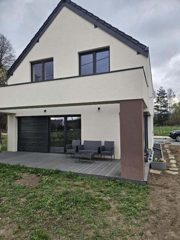 a white house with a deck with two chairs at Harmonia in Radochów