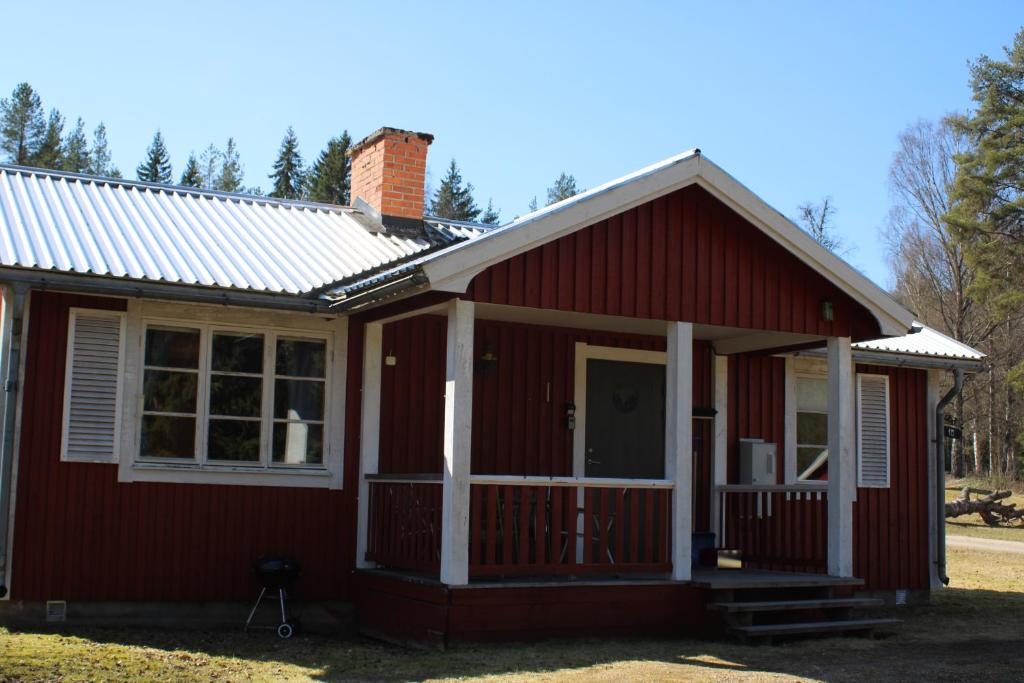 a red tiny house with a porch at Comfortable and cozy cottage in Sysslebäck