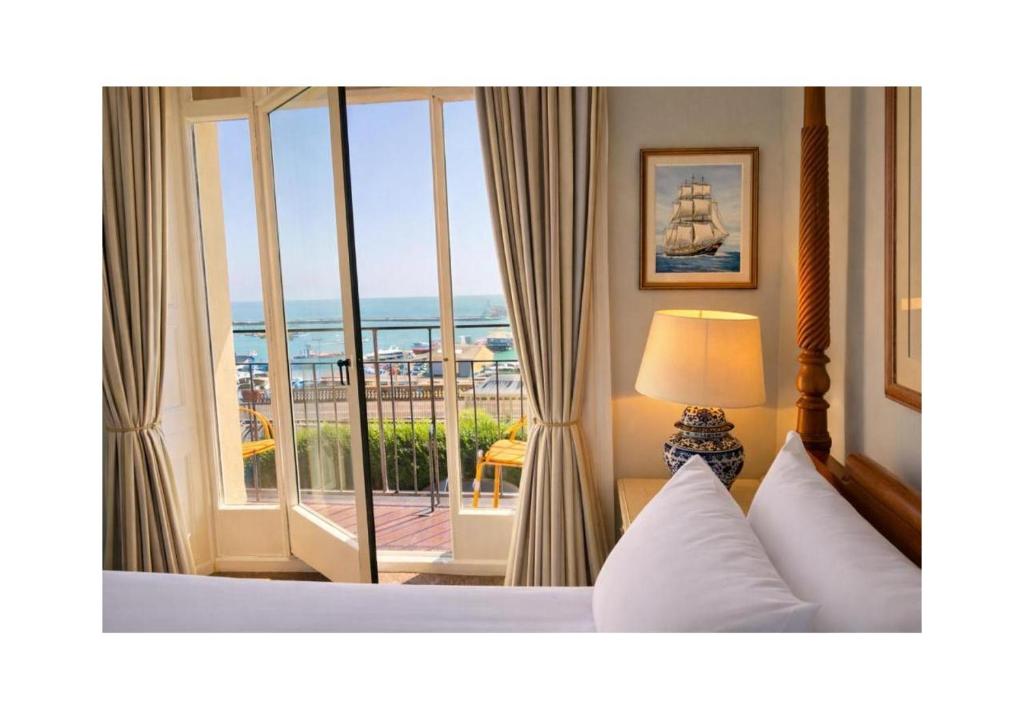 a bedroom with a large window with a view of the ocean at The Royal Harbour Hotel in Ramsgate