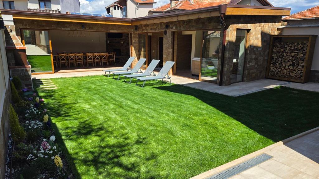 a lawn with lounge chairs on a house at Guest House Gogemi in Bansko