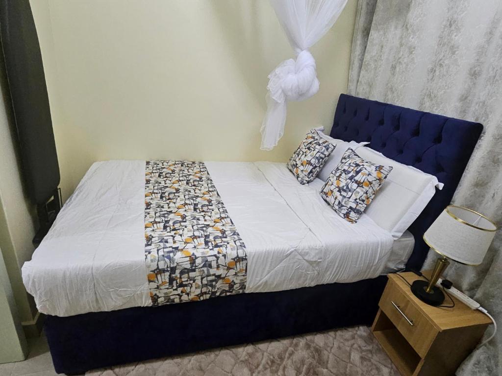 a bedroom with a bed with a blue headboard and pillows at Favoured Guest House in Nairobi