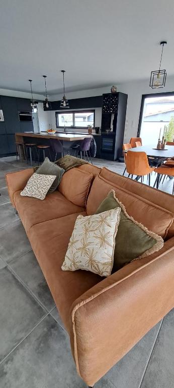 a brown couch with pillows on it in a room at Location maison confortable et cozi in Cazaux