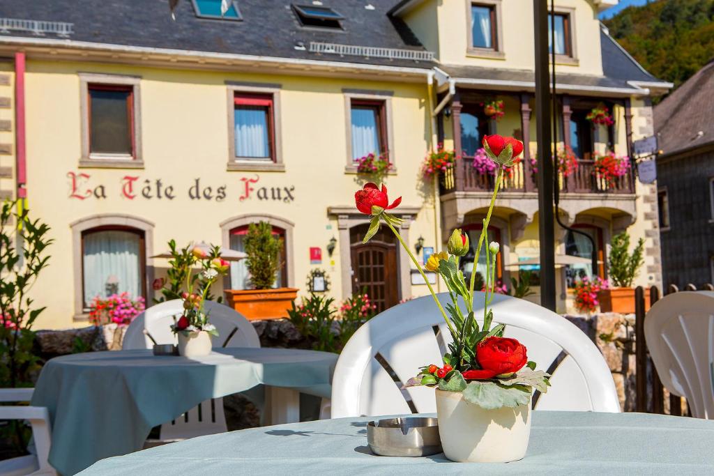 two tables with flowers in vases on them in front of a building at Logis Hôtel Restaurant La Tête Des Faux in Le Bonhomme