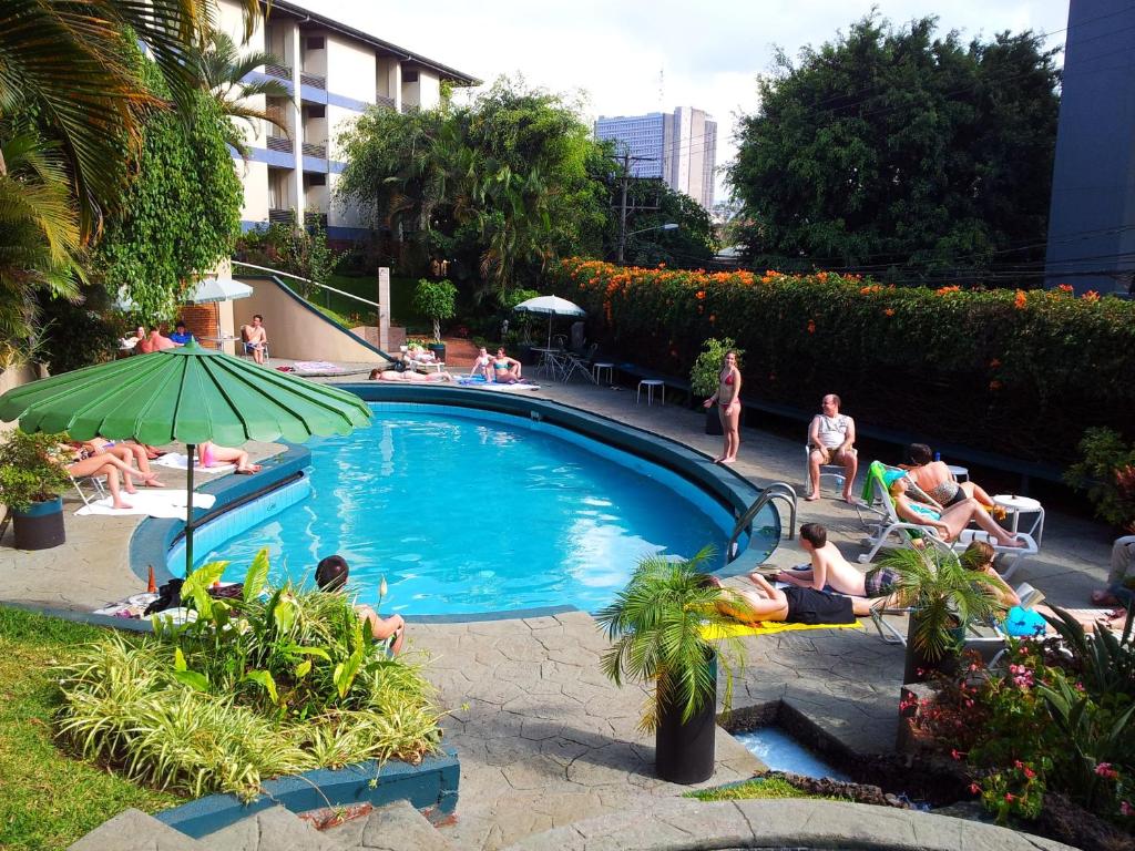 eine Gruppe von Menschen, die um einen Pool herum sitzen in der Unterkunft Hotel Villa Tournon in San José