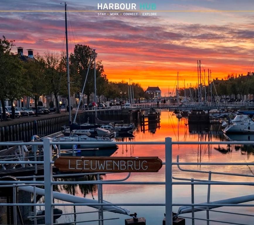 a marina with boats in the water at sunset at Harbour Hub Hotel in Harlingen