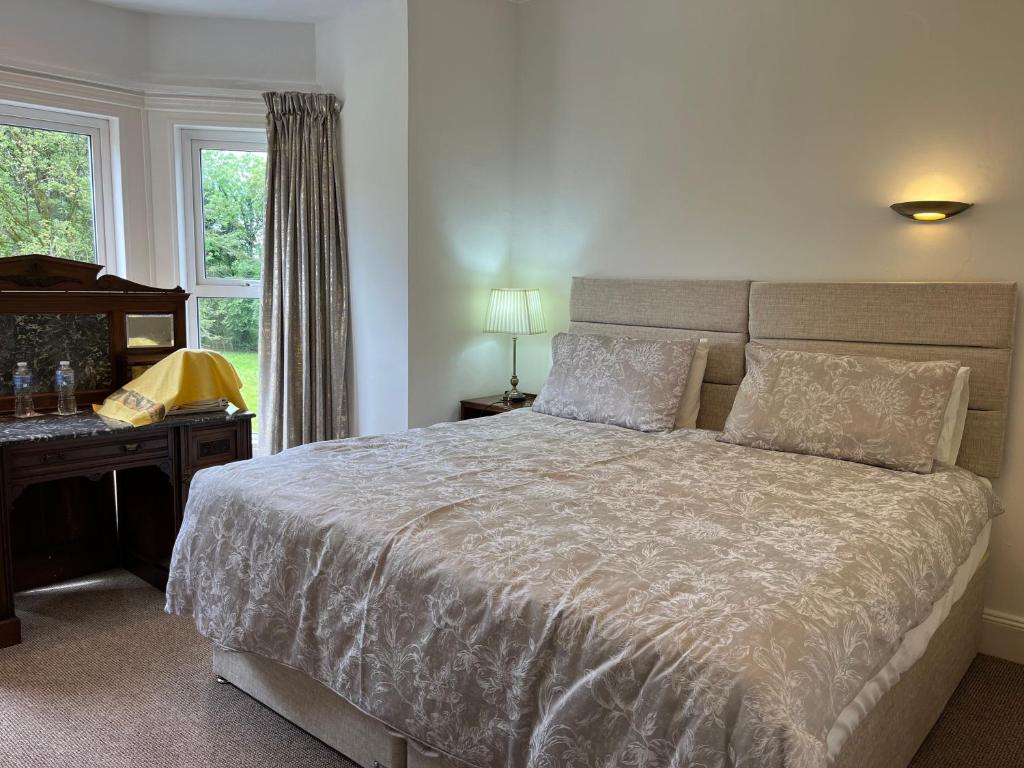 a bedroom with a bed and a desk and a window at Derryvree House in Maguires Bridge
