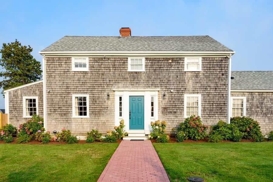 a gray brick house with a blue door at Luxurious Nantucket Getaway Heated Pool in Nantucket