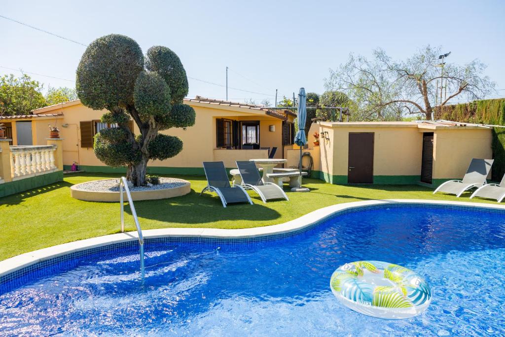 a swimming pool in a yard with chairs and a house at Casa L'Escala 30 in L'Escala