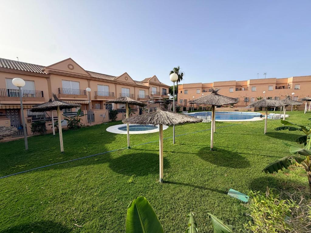 a group of umbrellas in a yard with a pool at Brisa de la Barrosa in Novo Sancti Petri