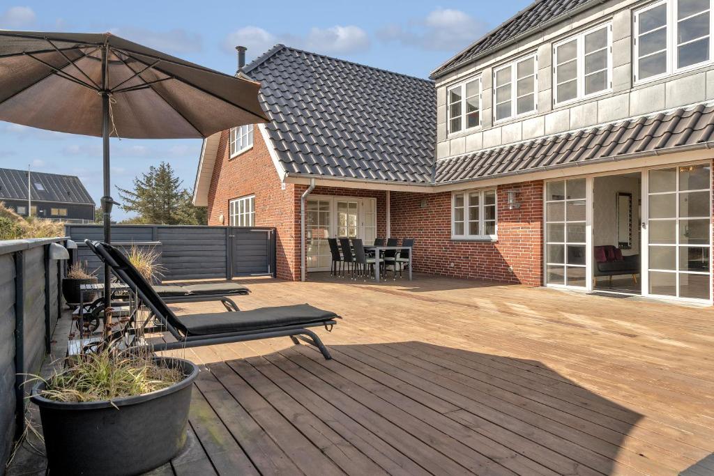 a patio with a chair and an umbrella and a house at Klithuset in Henne Strand