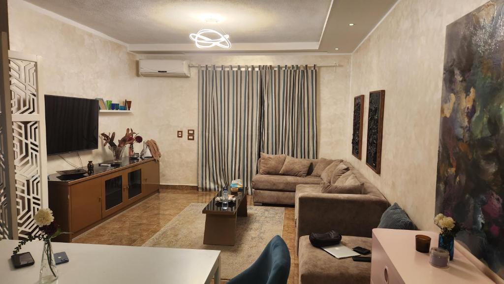 a living room with a couch and a tv at Maison Verde Madinaty in Cairo