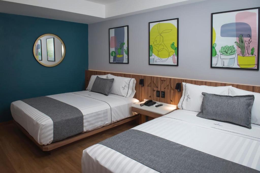 a room with two beds and a mirror at Hotel Flamencos Centro Histórico in Mexico City