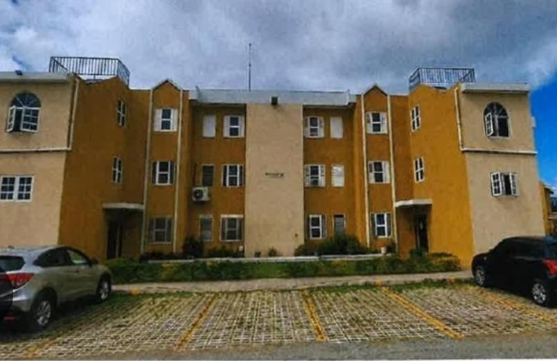 a large building with cars parked in a parking lot at Leemclean gated vacation home in Spanish Town