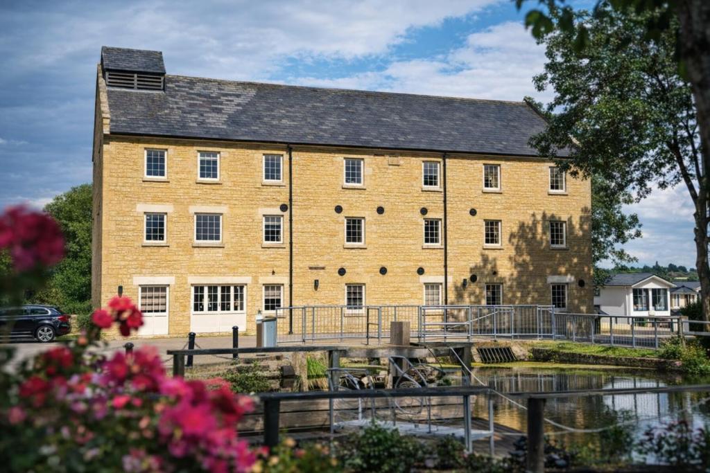 a large brick building next to a body of water at Yarwell Mill in Nassington