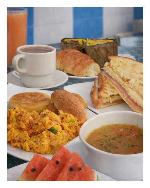 a table with plates of food and a cup of coffee at Hotel la Ciudad in Barrancabermeja