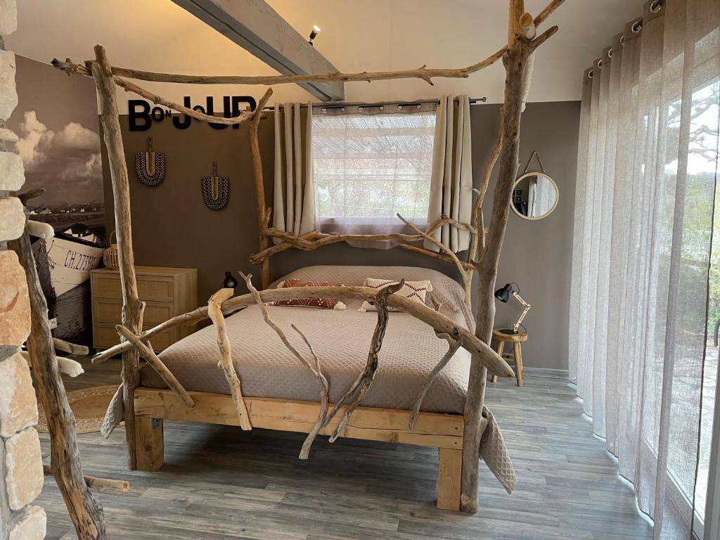 a bedroom with a bed made out of tree branches at Le petit cabanon in Lagorce