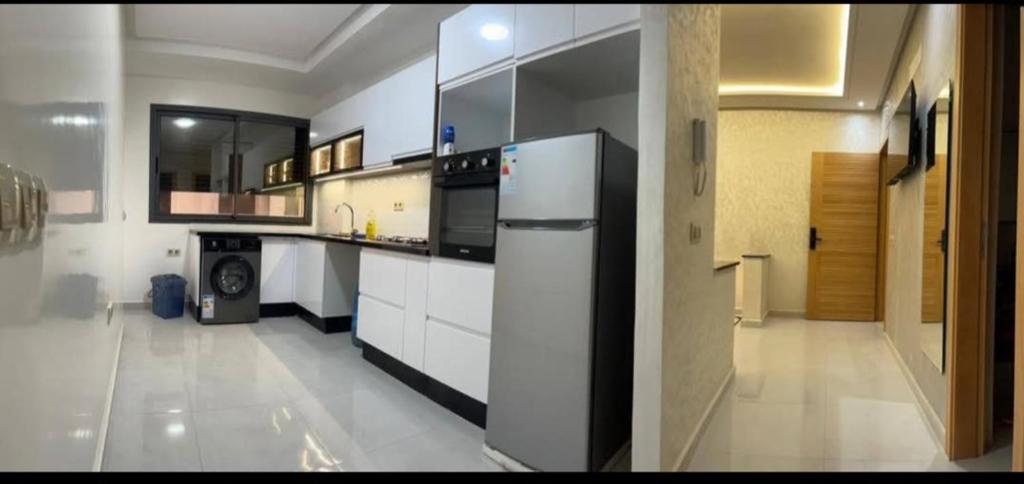 a kitchen with white cabinets and a refrigerator at Apparemment in Agadir