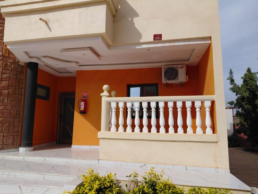 a house with an orange wall and a white staircase at Apparthotel Le SALY Beach yenne in Toubab Dialaw