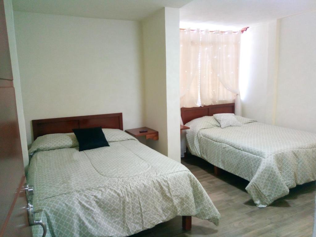 a bedroom with two beds and a window at Callihotel in Tehuacán