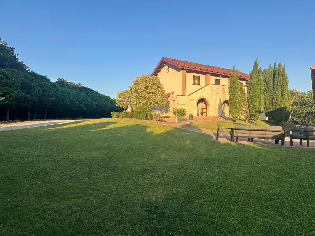 a large grass field with two benches in front of a building at Agriturismo Montebeltrano in Paterno Calabro