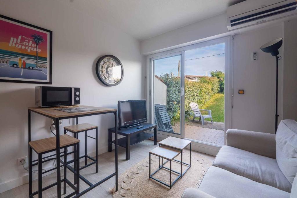a living room with a tv and a desk with a computer at Charmant studio climatisé à deux pas de la plage! in Anglet