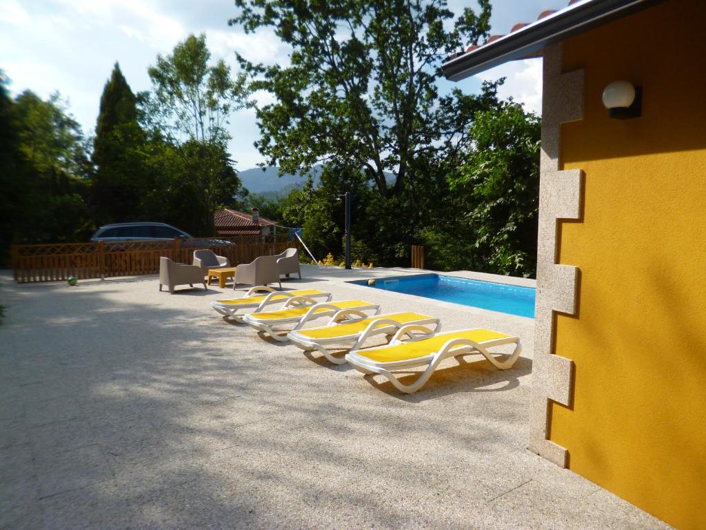 a row of yellow lounge chairs next to a swimming pool at Casinha de campo in Geres