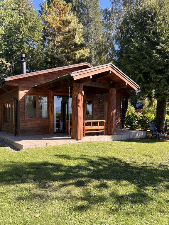 a wooden cabin in a park with a grass field at Cabaña Coihue in Pucará