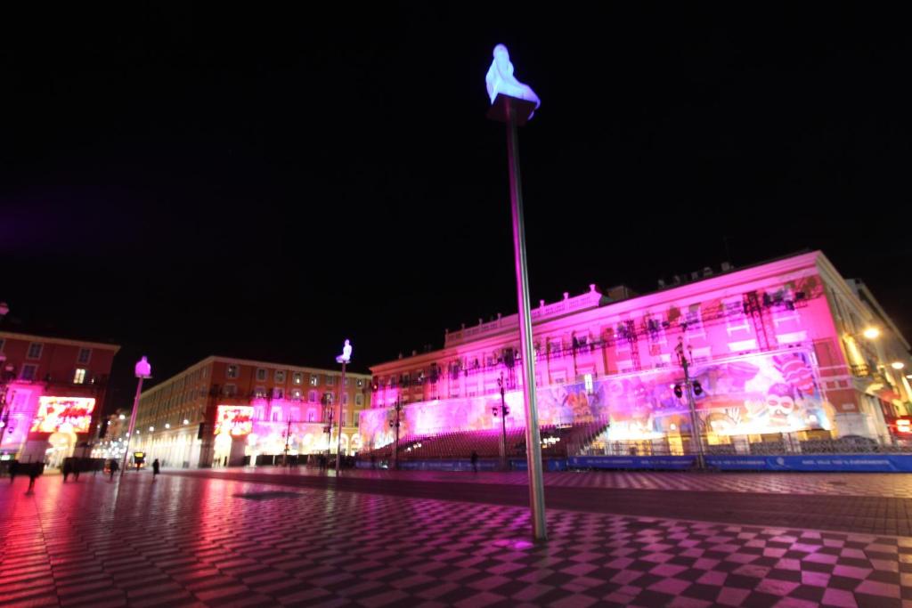 un edificio con luces rosas por la noche en Nice Massena, en Niza