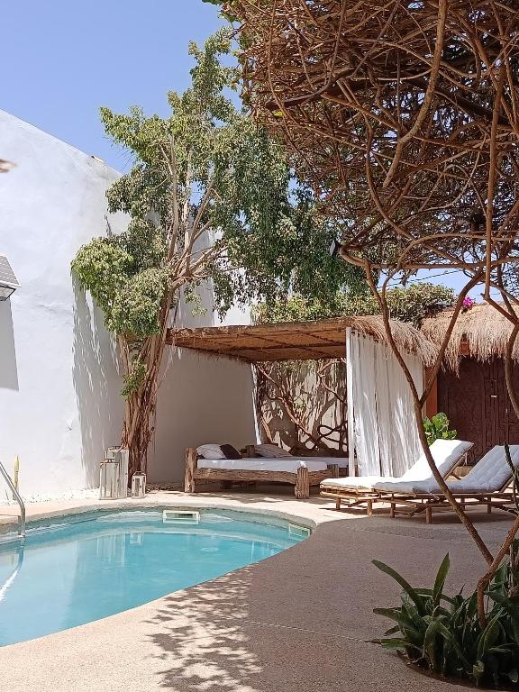 a resort with a swimming pool and a bed at Maison Talouma in Saly Portudal