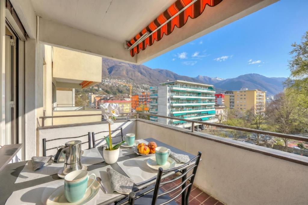 a table and chairs on a balcony with a view at Lido Apartment Locarno with Balcony and Parking - Happy Rentals in Locarno