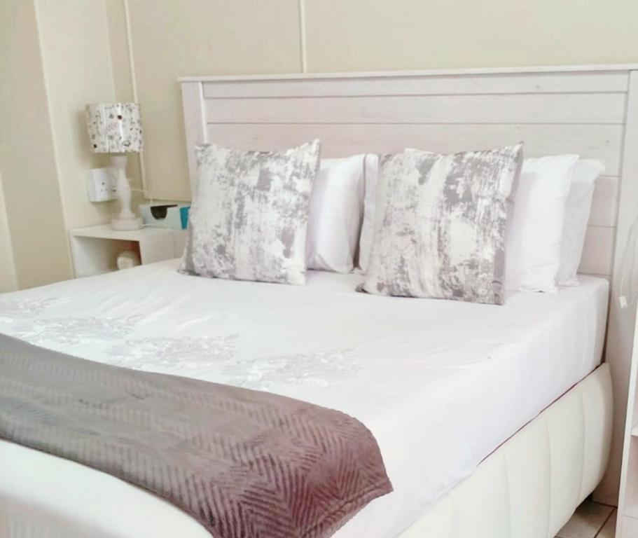 a bed with white sheets and pillows on it at Durban Oceanic Apartment 117 in Durban