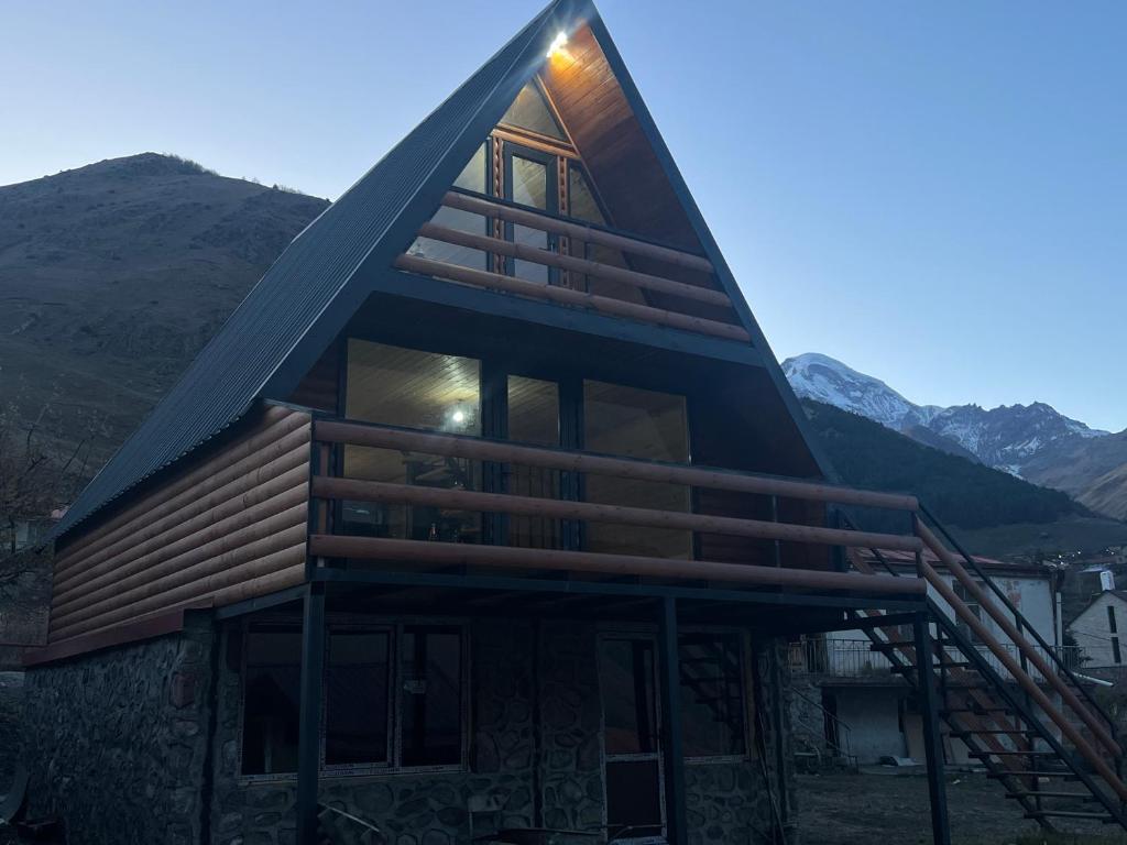a house with a triangle roof with mountains in the background at LizMari in (( Gergeti ))